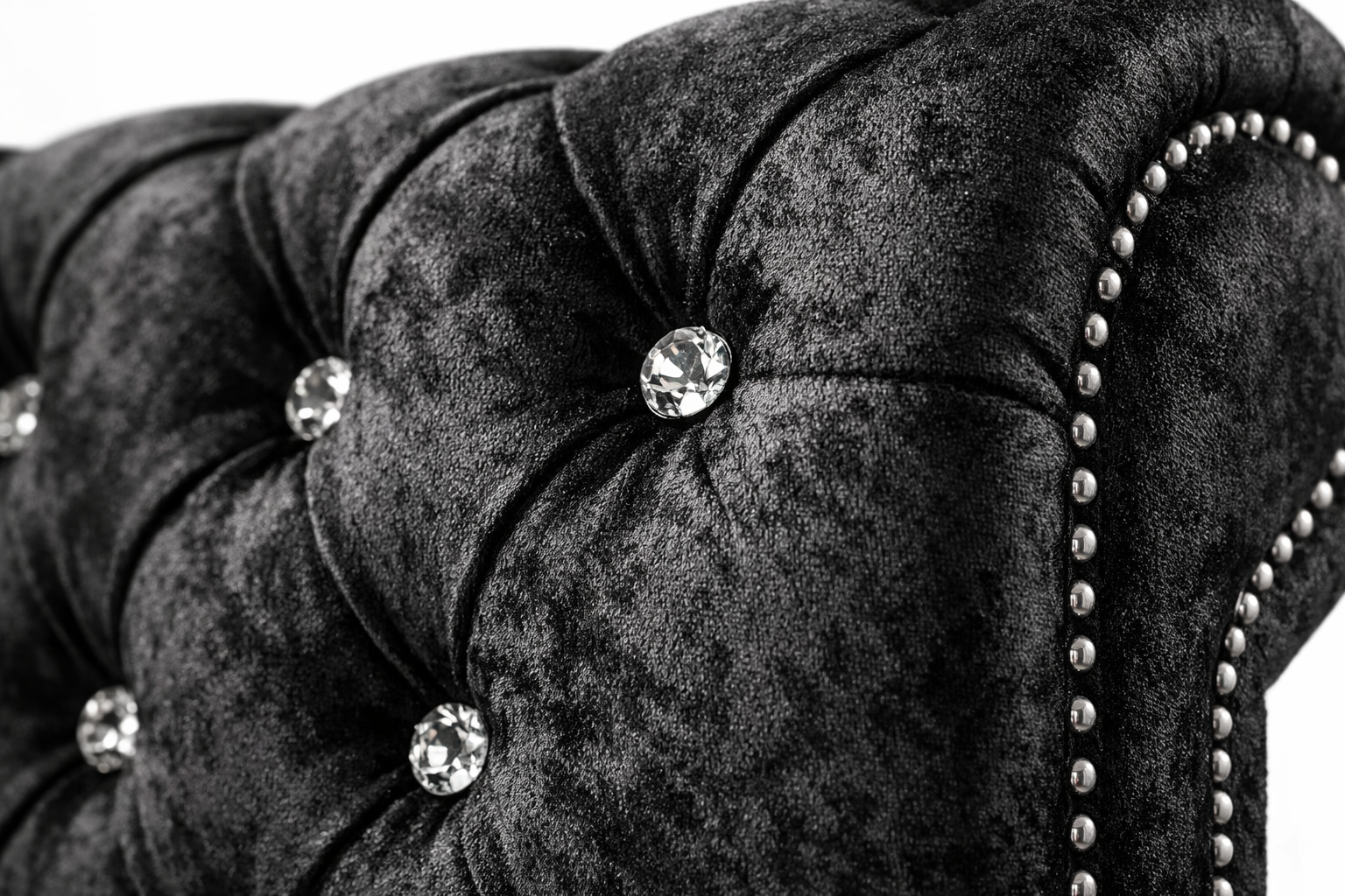 Close-up of a black velvet chair with crystal buttons and nailhead trim.