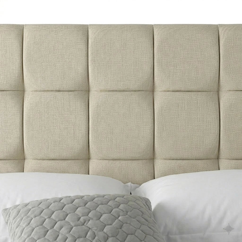 Beige upholstered headboard with white pillows and a textured gray pillow on a bed.