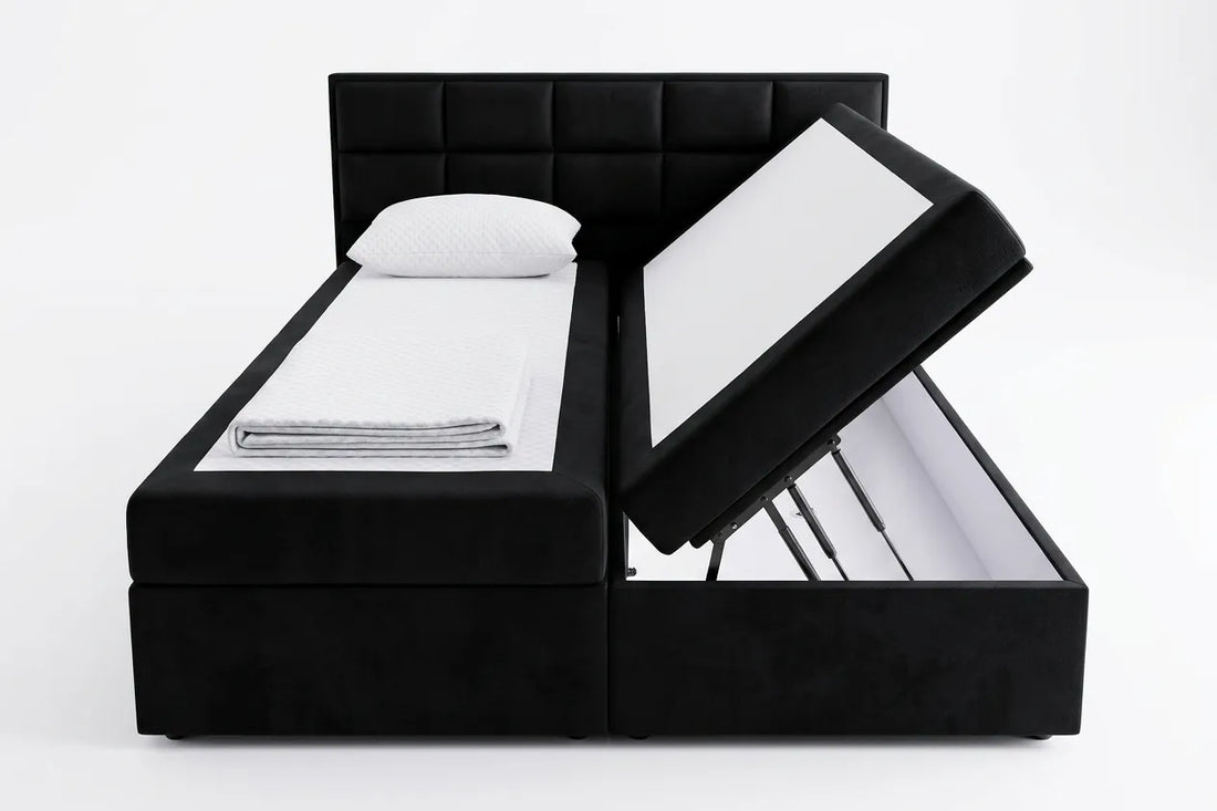 Black upholstered bed with open storage drawers on a white background